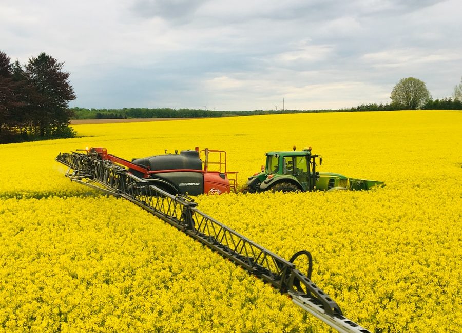 green tractor on yellow flower field during daytime