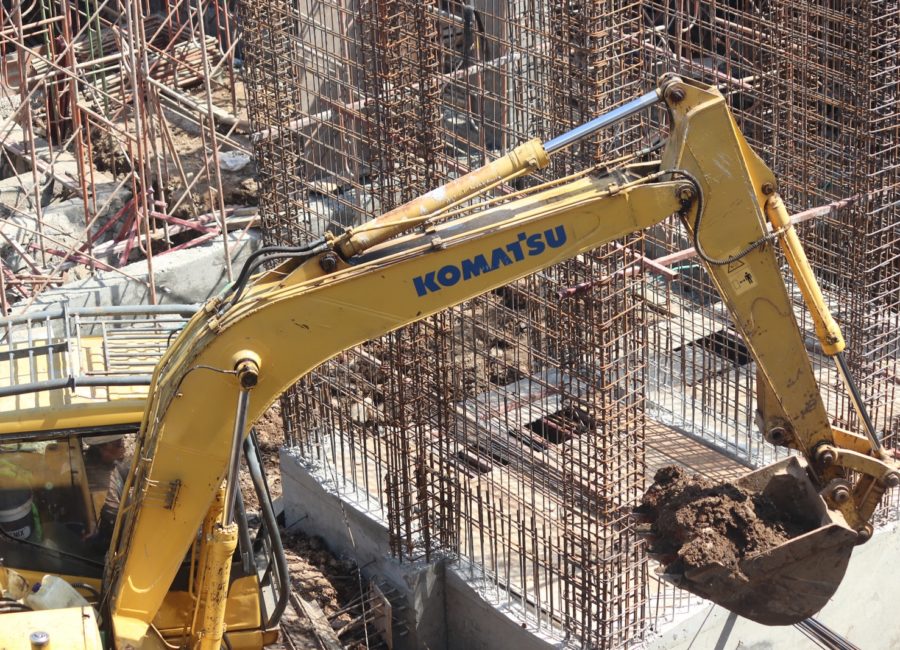 yellow excavator near gray metal fence during daytime